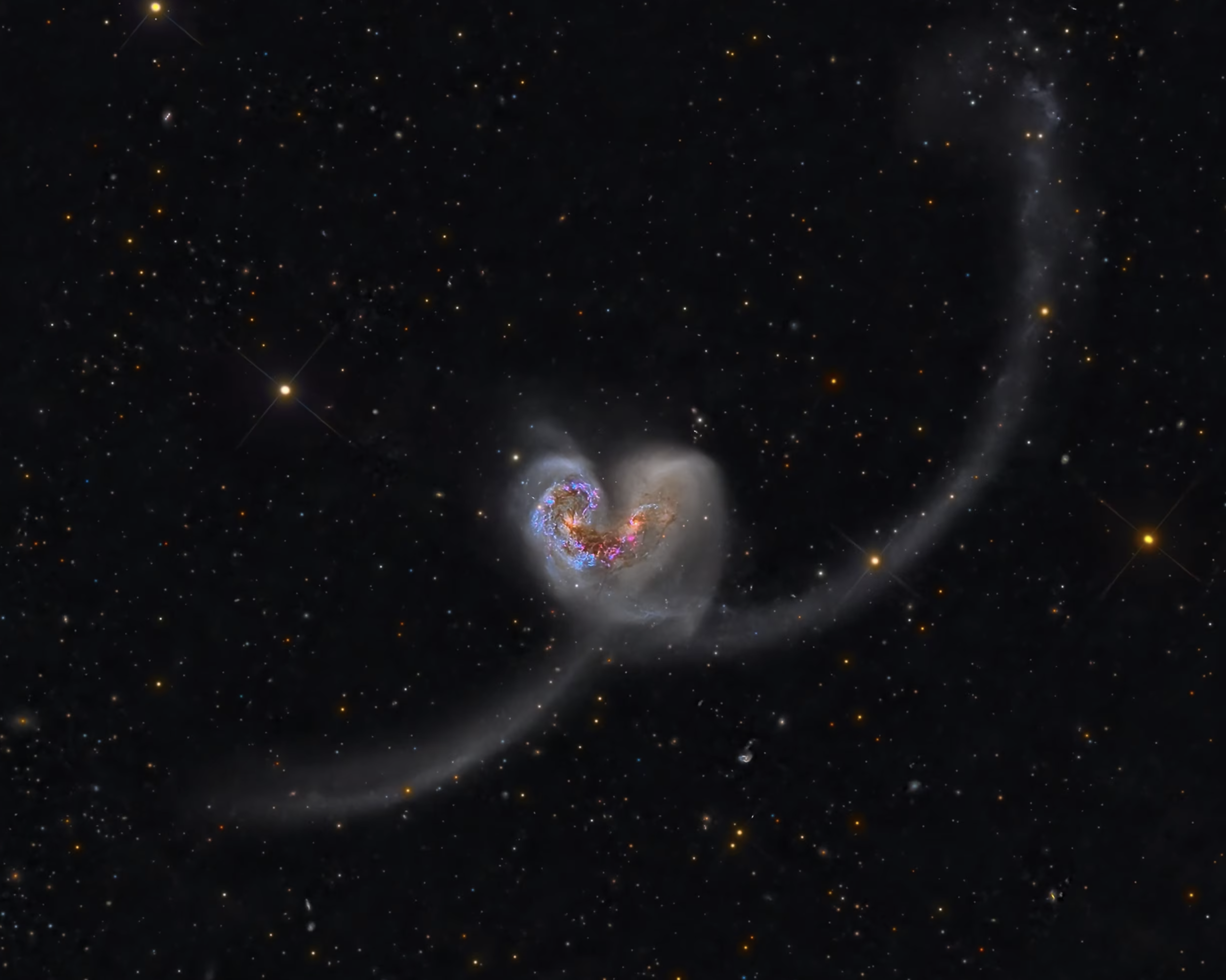 Galaxies NGC 4038 and NGC 4039, also known as the Antennae Galaxies, share a strong gravitational attraction, forming a heart shape.